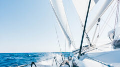 Sun shining from behind the sails of a yacht.