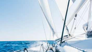 Sun shining from behind the sails of a yacht.