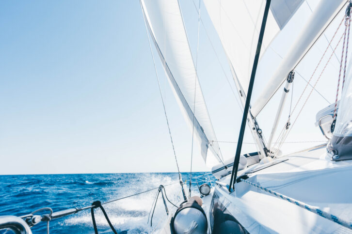 Sun shining from behind the sails of a yacht.