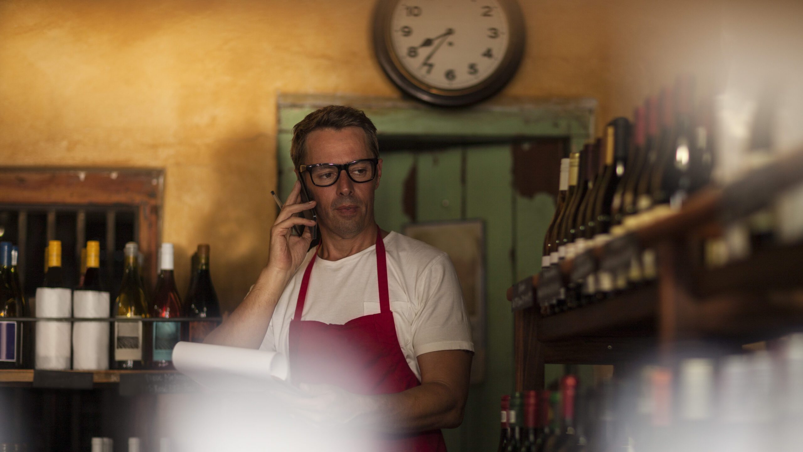 Man working in wine shop making telephone call
